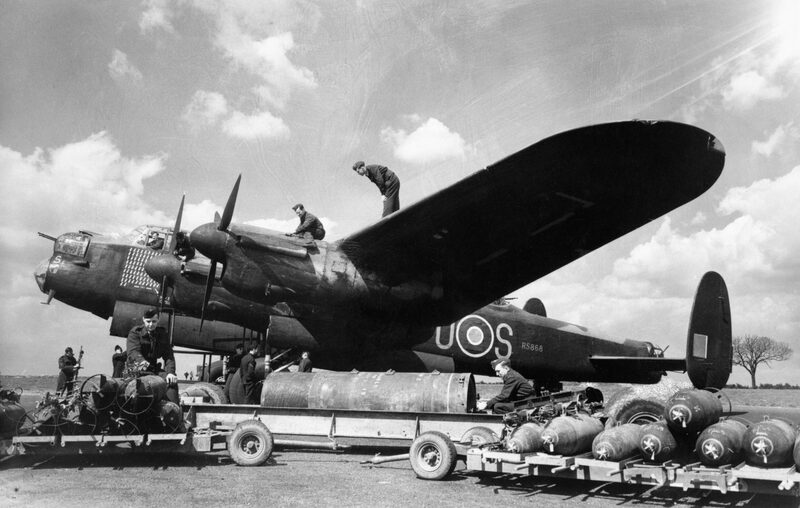 Ground crew working on the veteran Lancaster 'S for Sugar' of No. 467 Squadron RAAF at Waddington in 1944, with a trolley of bombs beside the fuselage.