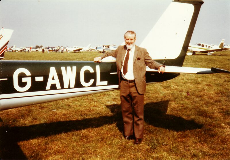 E G White in a tweed jacket standing beside the tail of his Cessna 150, G-AWCL, on the grass at Cranfield air show, September 1981.
