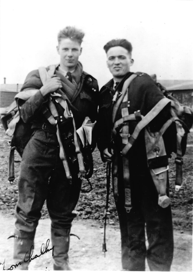 E G White and his pilot Sgt E A Lampkin in flying kit, carrying parachutes and harness, on a muddy airfield at Hibaldstow in autumn 1942.